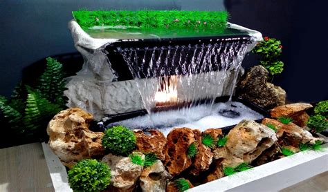 a fountain with water flowing from it surrounded by rocks and plants in ...