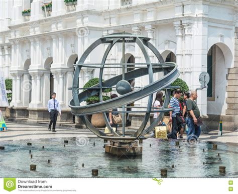 Tourists Walk Pass the Metal Globe Statue in the Fountain at the Senado Square in Macau, China ...