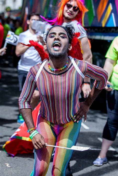 Someone celebrating Pride in London un a very colourful rainbow outfit. He is wearing it all ...