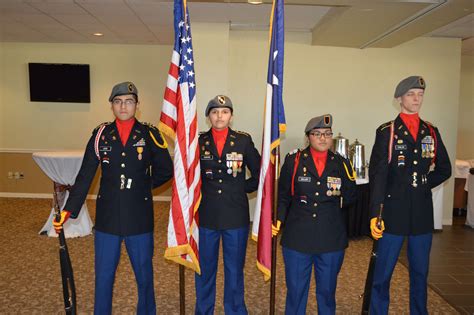 four men in uniform standing next to two american flags