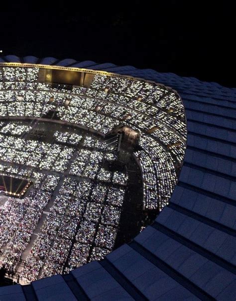 an aerial view of a stadium at night with lights on the roof and in the stands