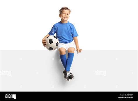 Cute little boy in a blue soccer jersey sitting on a blank panel and ...