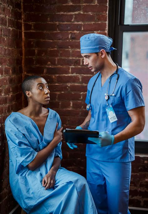 Doctor communicating with black patient in hallway of hospital · Free Stock Photo