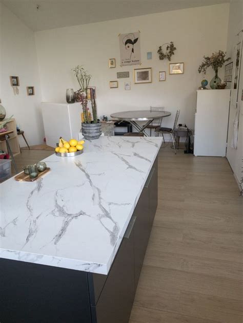 a kitchen with white marble counter tops next to a dining room table and chairs in the background