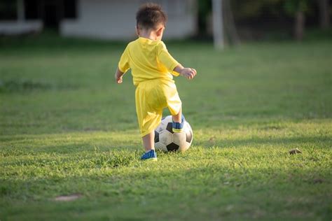 Premium Photo | Little boy playing football in the field