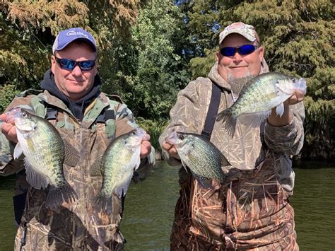 two men holding up some fish in their hands while standing next to each other on the water