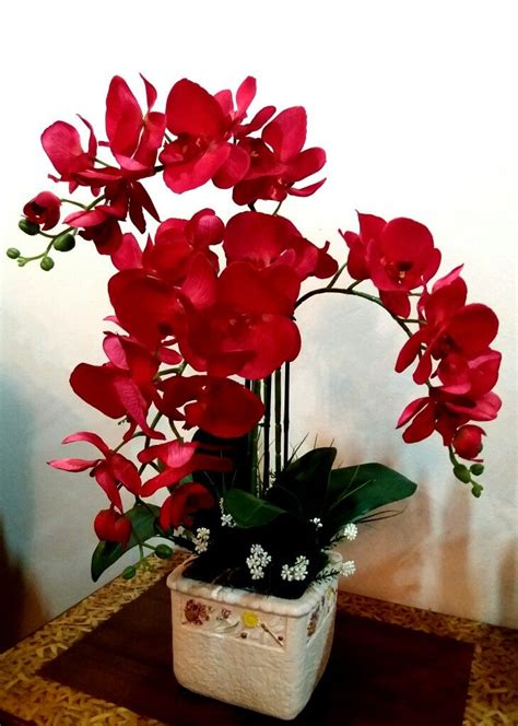 red flowers are in a white vase on a table
