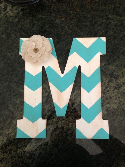 the letter m is made out of wood and has a flower on top of it