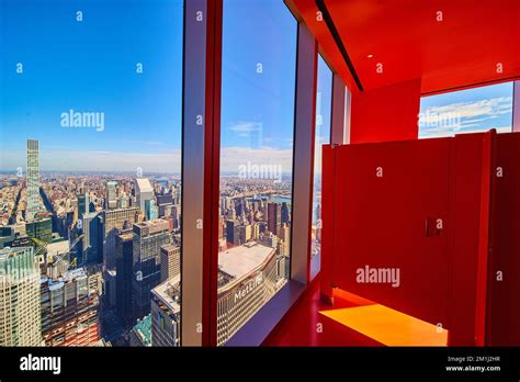 Surreal orange bathroom stall with windows overlooking New York City skyline high up Stock Photo ...