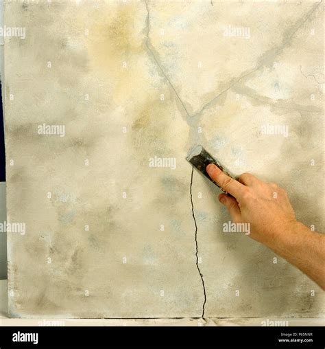 Filling a crack in a wall with filler Stock Photo - Alamy