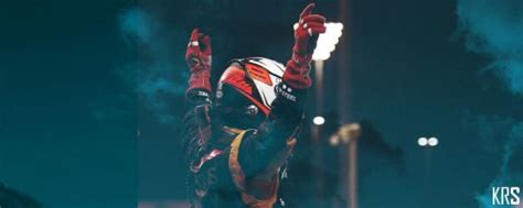 a motorcyclist doing a trick in the air with his hands up at night