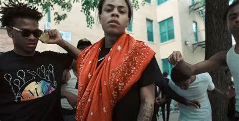 two men standing next to each other in front of a building and one man wearing an orange scarf