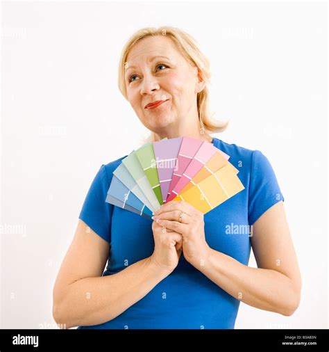 Portrait of smiling adult blonde woman holding paint swatches with hopeful expression Stock ...