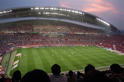 a soccer stadium filled with lots of people watching a game on the field at night