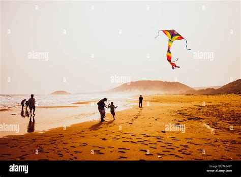 Capturar la atmósfera de siluetas de personas jugando y volar una cometa en la hermosa playa de ...