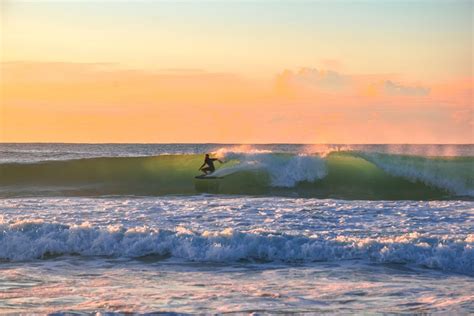 A surfer riding a wave at sunset · Free Stock Photo