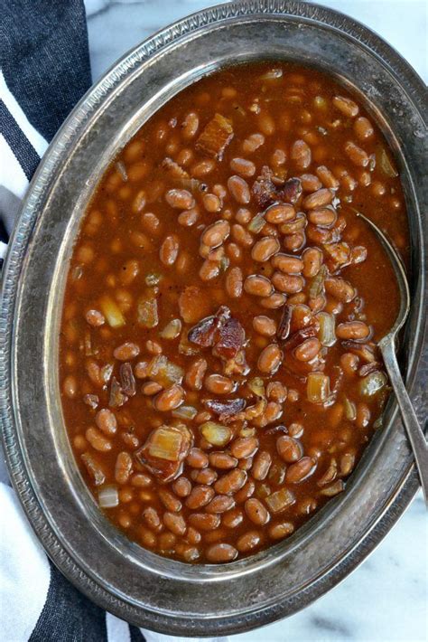 a metal bowl filled with beans on top of a white table cloth next to a ...