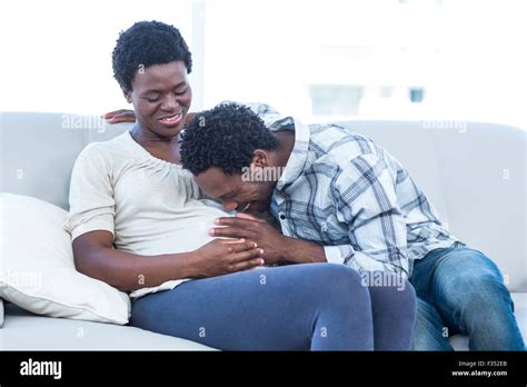 Happy pregnant woman with husband kissing her belly at home Stock Photo ...