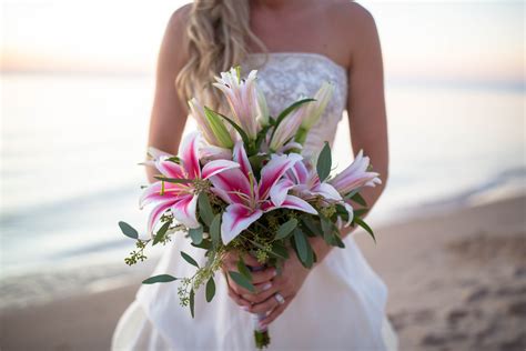 a bride holding a bouquet of flowers on the beach