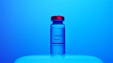 A Close-Up View of a Covid-19 Vaccine Vial on Blue Background · Free Stock Photo