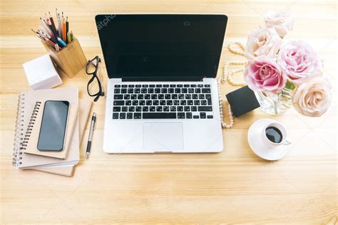 Girly office desktop with blank laptop screen, flowers, coffee ...