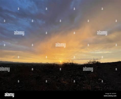 Wide expanse blue and gold dawn over the desert, sunrise peeking behind ...