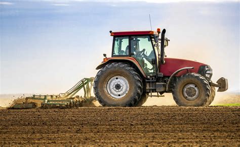 Farmer in tractor plowing field in spring stock photo