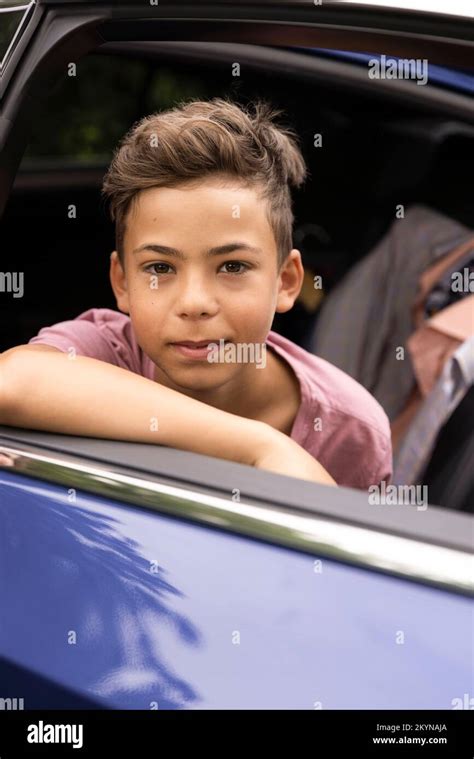 Portrait of boy leaning on car door seen through window Stock Photo - Alamy