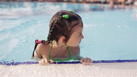 Little girl having fun in a swimming pool, first time learning to swim ...