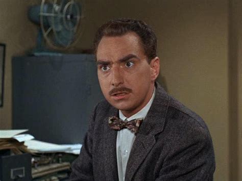 a man in a suit and bow tie sitting at a desk