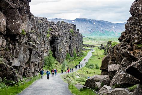 many people are walking on the path between two large rocks