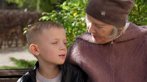 An Old Elderly Grandmother is Sitting on a Park Bench with Her Little Grandson. Stock Footage ...