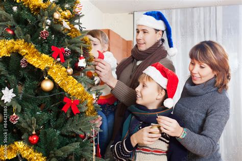 Happy family of four with Christmas tree Stock Photo | Adobe Stock