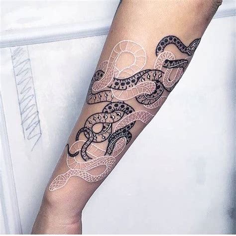 Black and white snake tattoos on the left forearm.