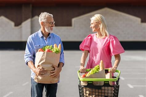 Premium Photo | Positive elderly man and woman rolling shopping cart with food