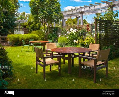 Landscaped Garden with Wooden Dining Table Set in the Shade of Trees Stock Photo - Alamy