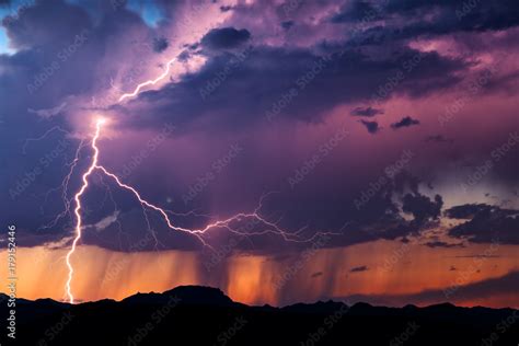 Lightning illuminates a thunderstorm at sunset Stock Photo | Adobe Stock