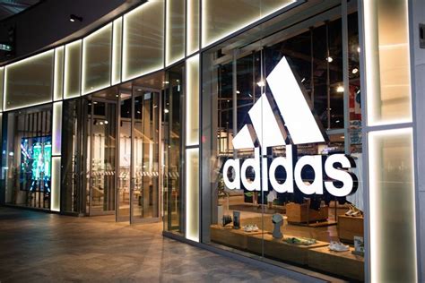 the adidas store is lit up at night with its logo reflected in the glass