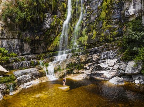 Aerial view of a woman standing in front of a waterfall in black swimsuit, Rawsonville, Western ...