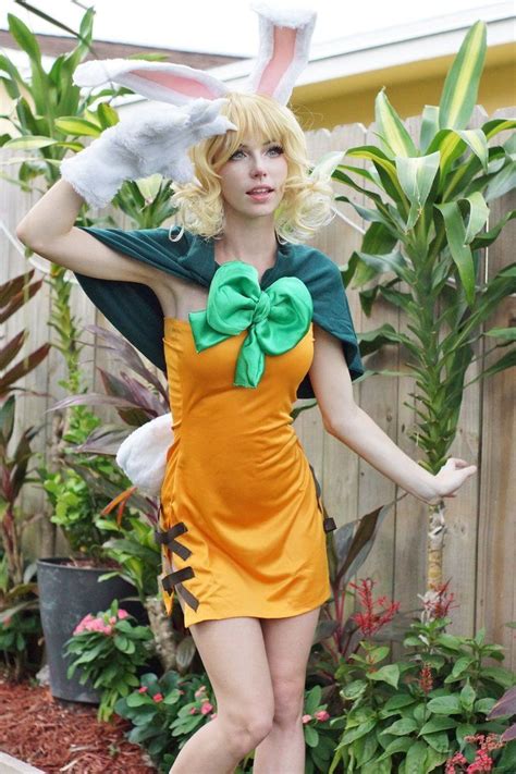 a woman dressed in an orange dress and bunny ears with her hands behind ...