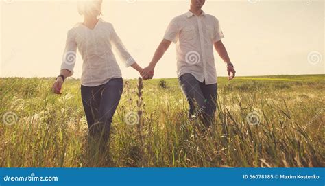 Happy Couple Holding Hands Walking through a Meadow Stock Image - Image of happy, outside: 56078185