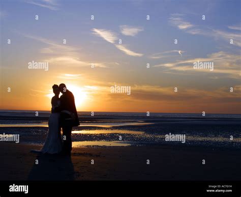 a couple holding each other on a beach at sunset Stock Photo - Alamy