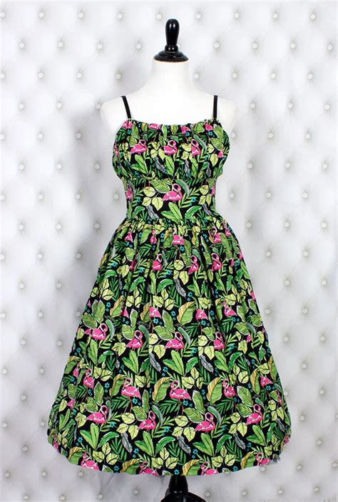 This fun dress featuring an all-over flamingo print in a pretty shade of green with pink and ...