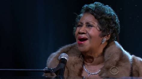 a woman in a fur coat singing into a microphone