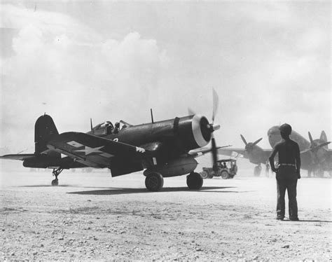 F4U-1 Corsair of Marine Squadron VMF-114 set for take-off from Peleliu, late 1944. Note C-46 ...