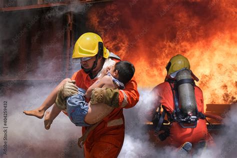 Firefighter holding child boy to save him in fire and smoke,Firemen ...