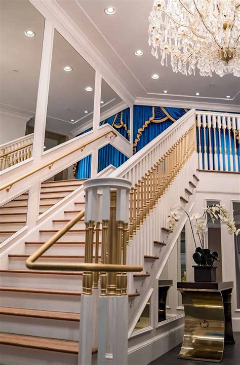 an elegant staircase with chandelier and white railings in a large room ...