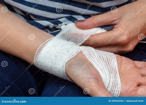 Young Woman Bandaging Her Wrist. Wound Care Bandage, Control Bleeding. Bandaging a Wrist Wound ...