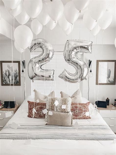 a bed topped with lots of white balloons next to a wall mounted number ...