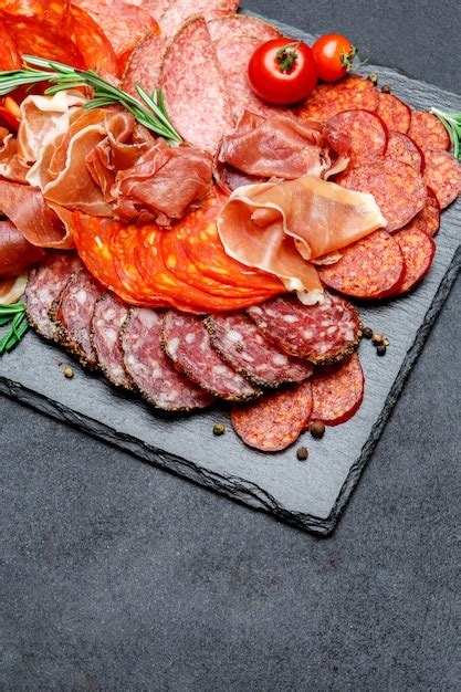 Premium Photo | Various types of dried organic salami sausage and parma on concrete surface